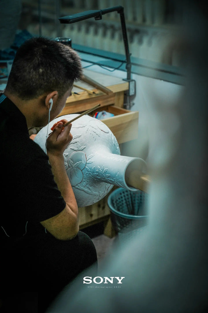 A craftsperson working on the raised decoration of a porcelain vessel