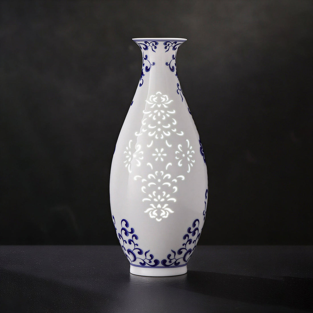 Contemporary Azure Blanc linglong vase with blue scroll decoration and illuminated floral patterns against a dark background.