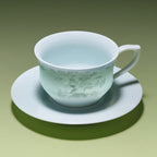 Pale blue-green porcelain coffee cup with horse-and-cloud decoration on its matching saucer.