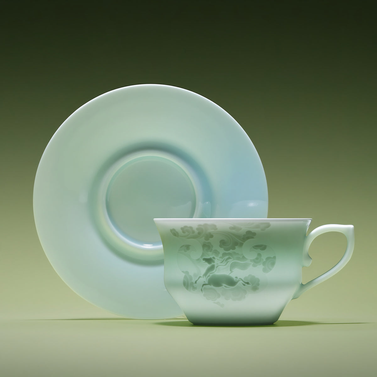 Front view of a pale Qingbai horse-pattern cup with its matching saucer standing behind it.
