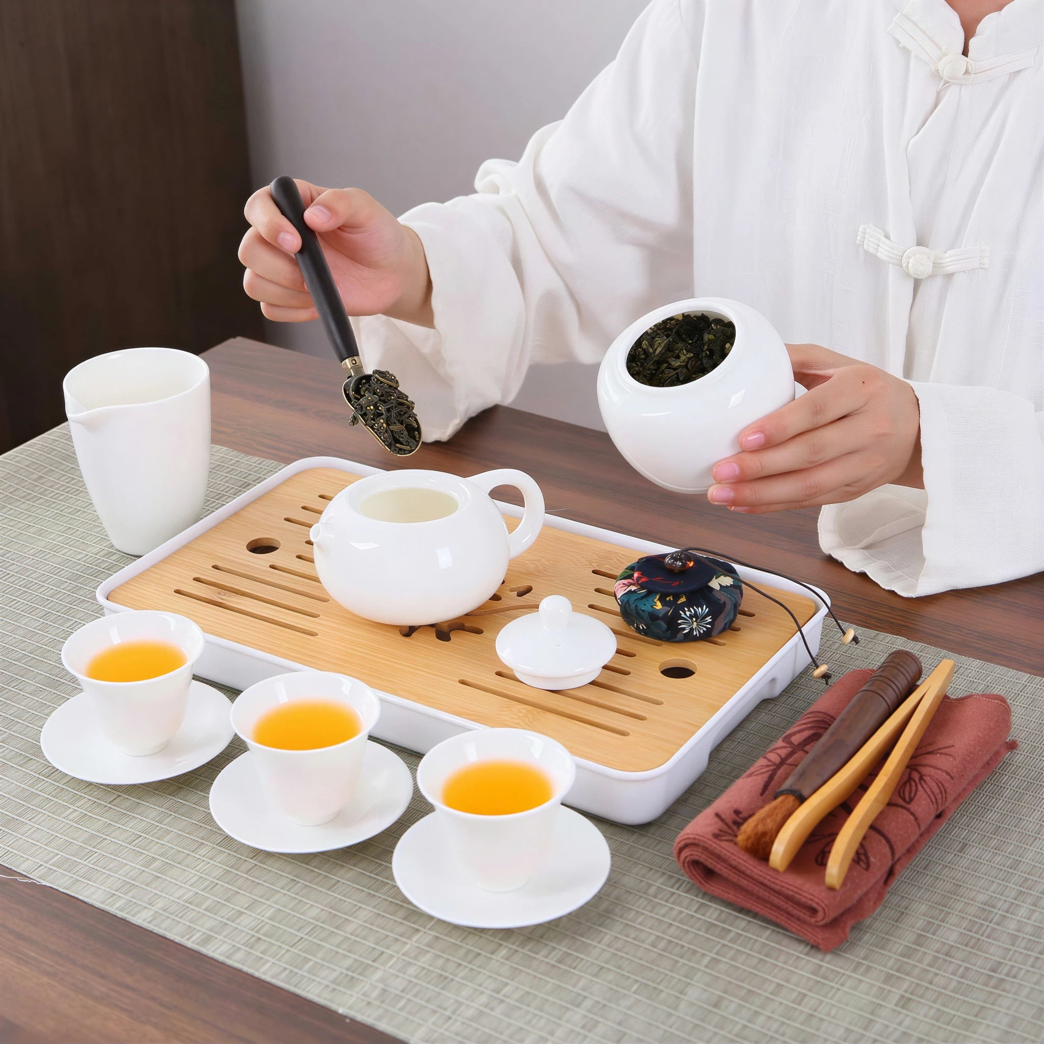 Tea leaves being added to the white porcelain Xishi teapot