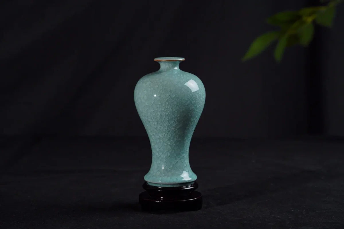 Green crackle-glazed vase with a narrow waist on a dark wooden stand