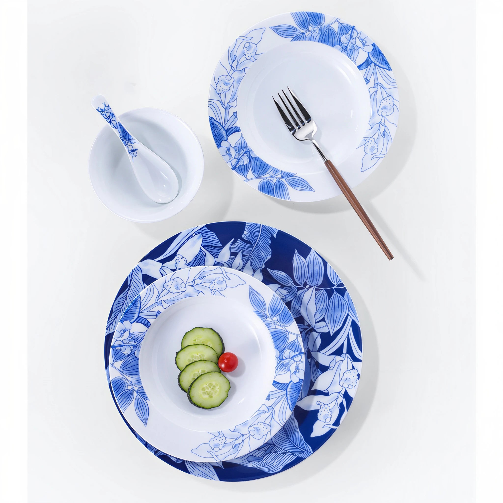 Overhead Deep Forest place setting with blue botanical plates, bowl, and porcelain spoon.