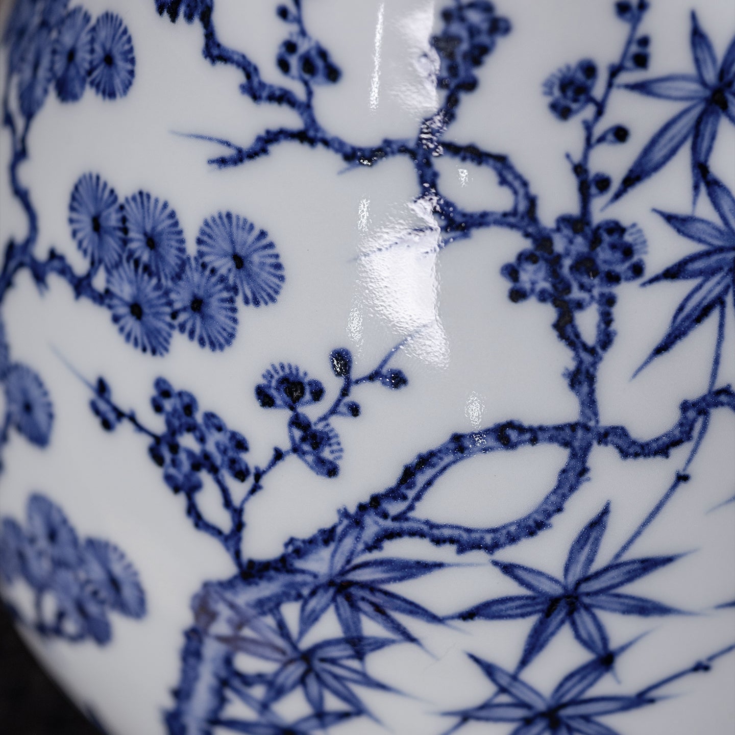 Close detail of cobalt pine, bamboo and plum brushwork beneath a glossy clear glaze