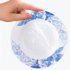 Water droplets on a glazed white porcelain plate with a blue floral border.
