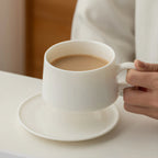 Hand holding the rounded loop handle of the Dehua white porcelain coffee cup