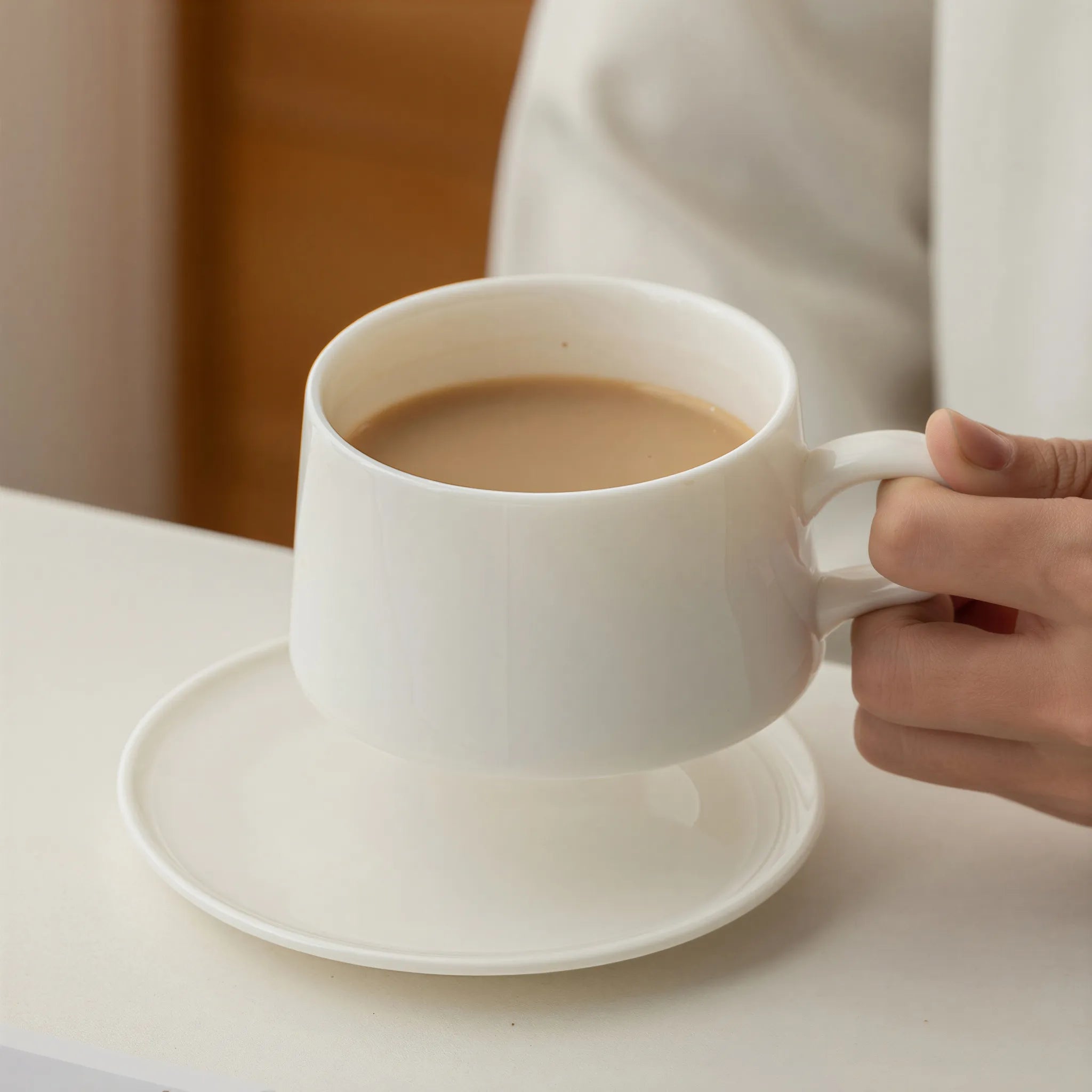 Hand holding the rounded loop handle of the Dehua white porcelain coffee cup