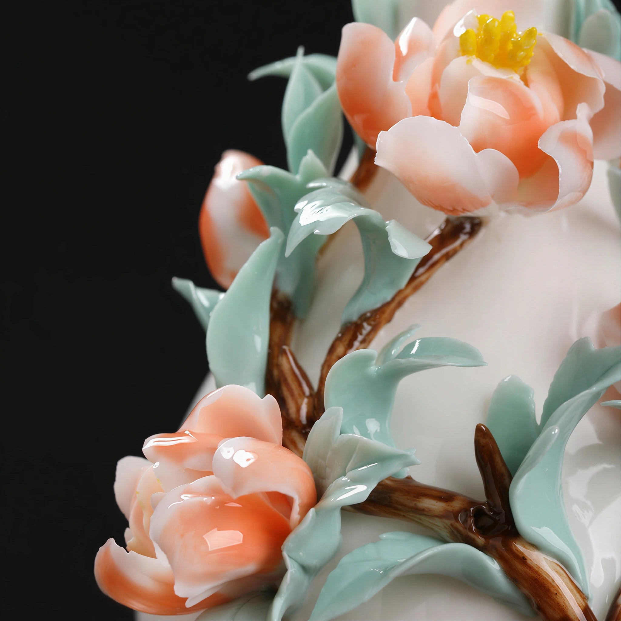 Close view of coral-peach ceramic peonies and celadon-green leaves