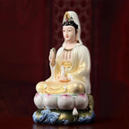 Gold-toned Guanyin above a polychrome lotus-and-wave base