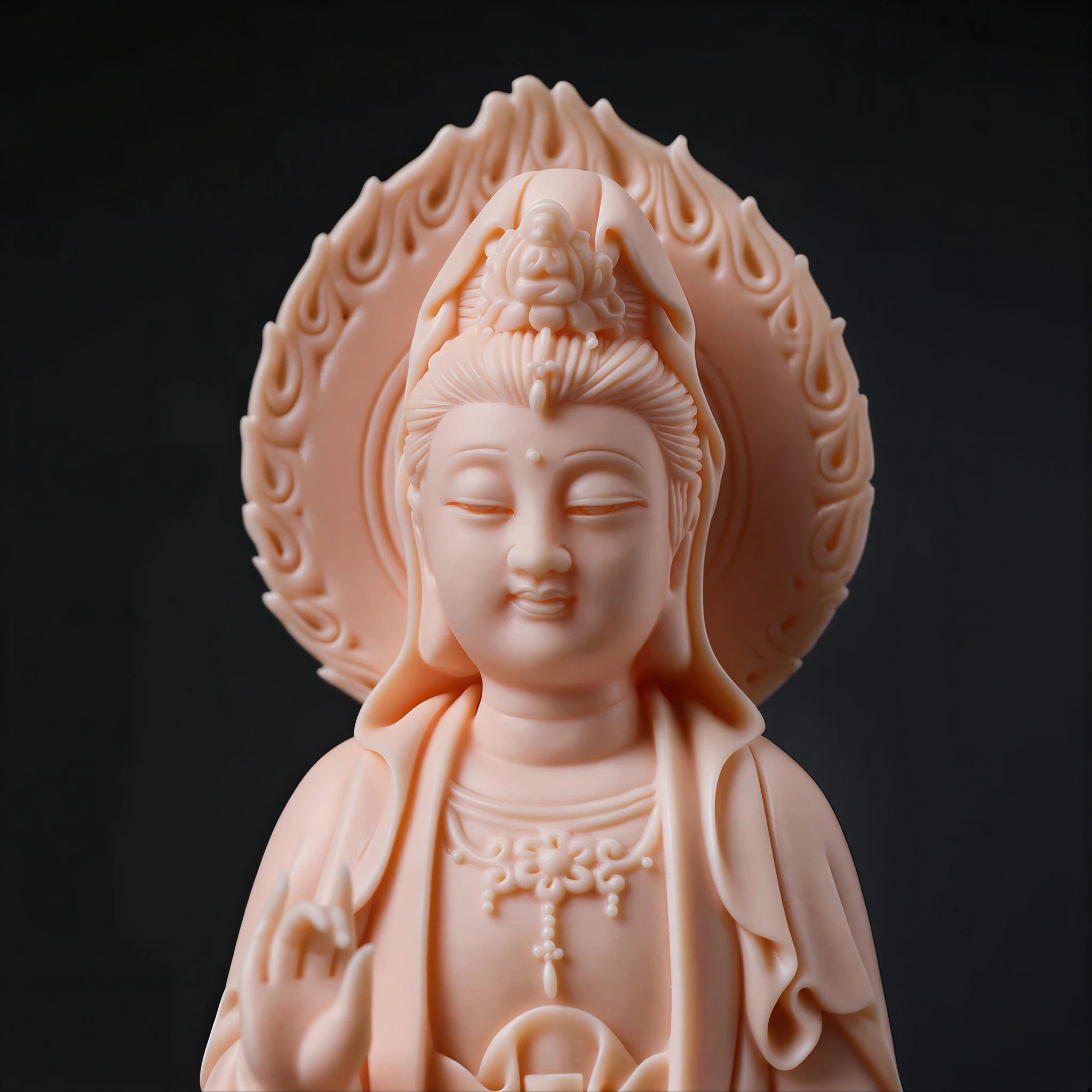 Close view of the Guanyin face and carved mandorla in warm blush porcelain