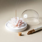 White porcelain lotus holding incense beside its clear dome