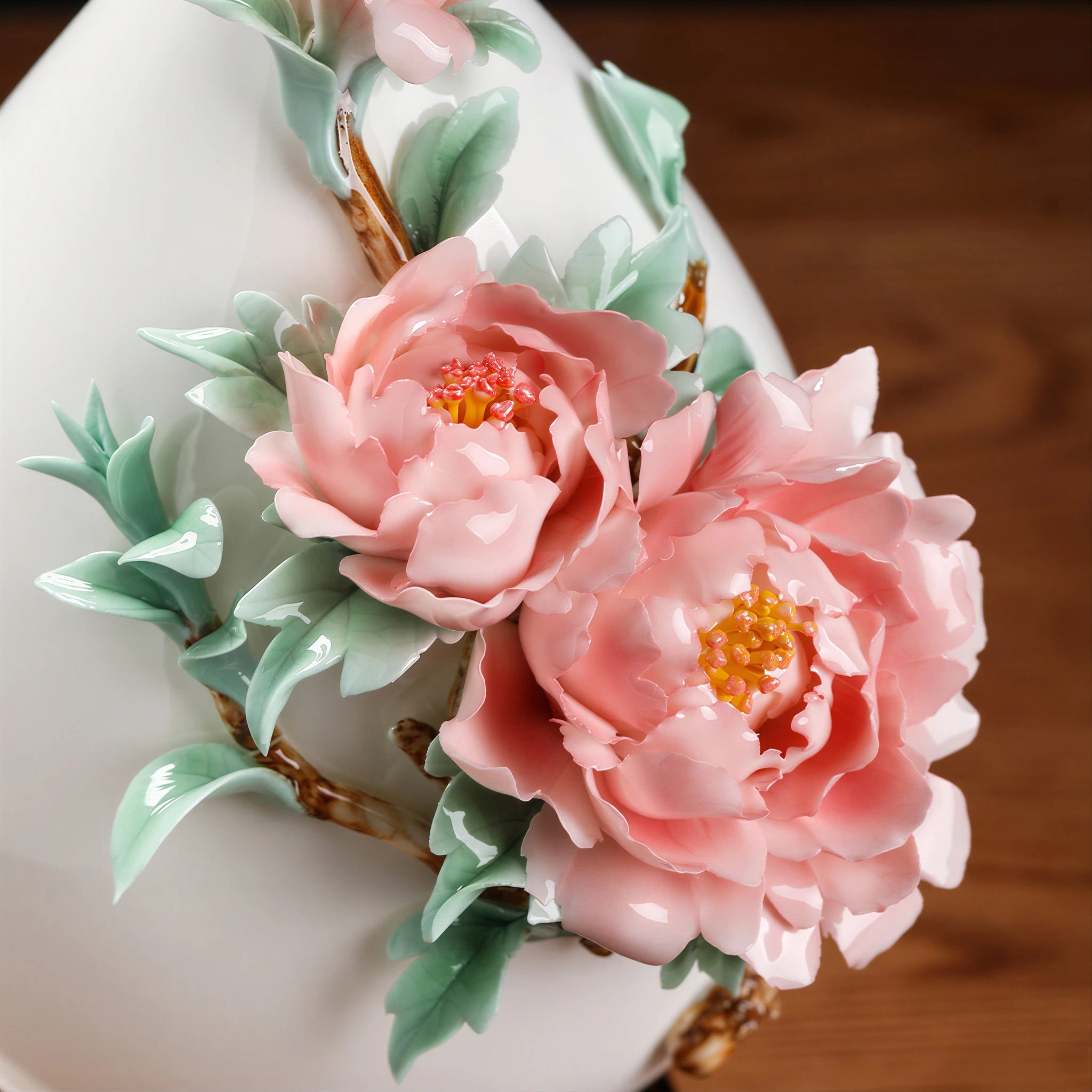 Close view of layered pink ceramic peony petals and pale green leaves