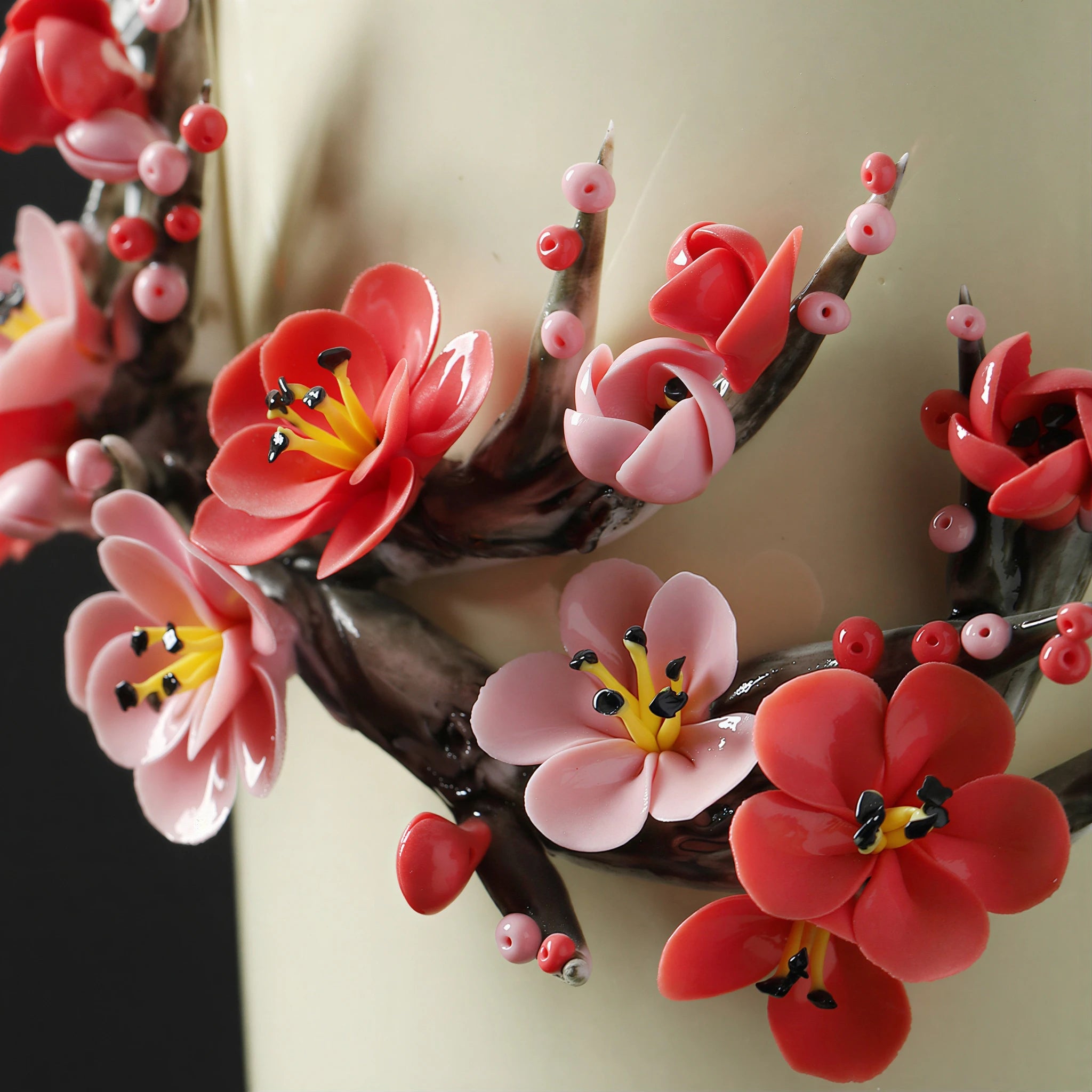 Close view of red and blush ceramic plum blossoms with dark stamens