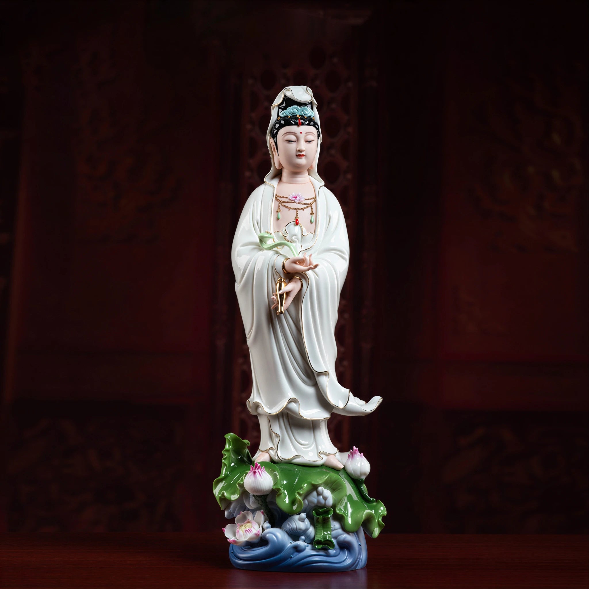 Front view of standing white Guanyin with gold-toned details and ruyi