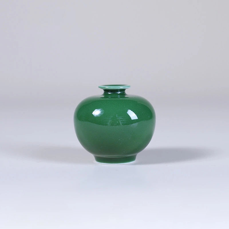 Front view of a rounded emerald-green pomegranate-form porcelain vase.