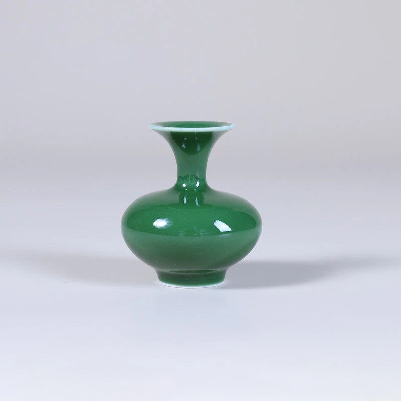 Front view of a low emerald-green squat porcelain vase with flared mouth.