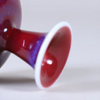 Close view of a flared white foot and glossy rose-purple glaze.