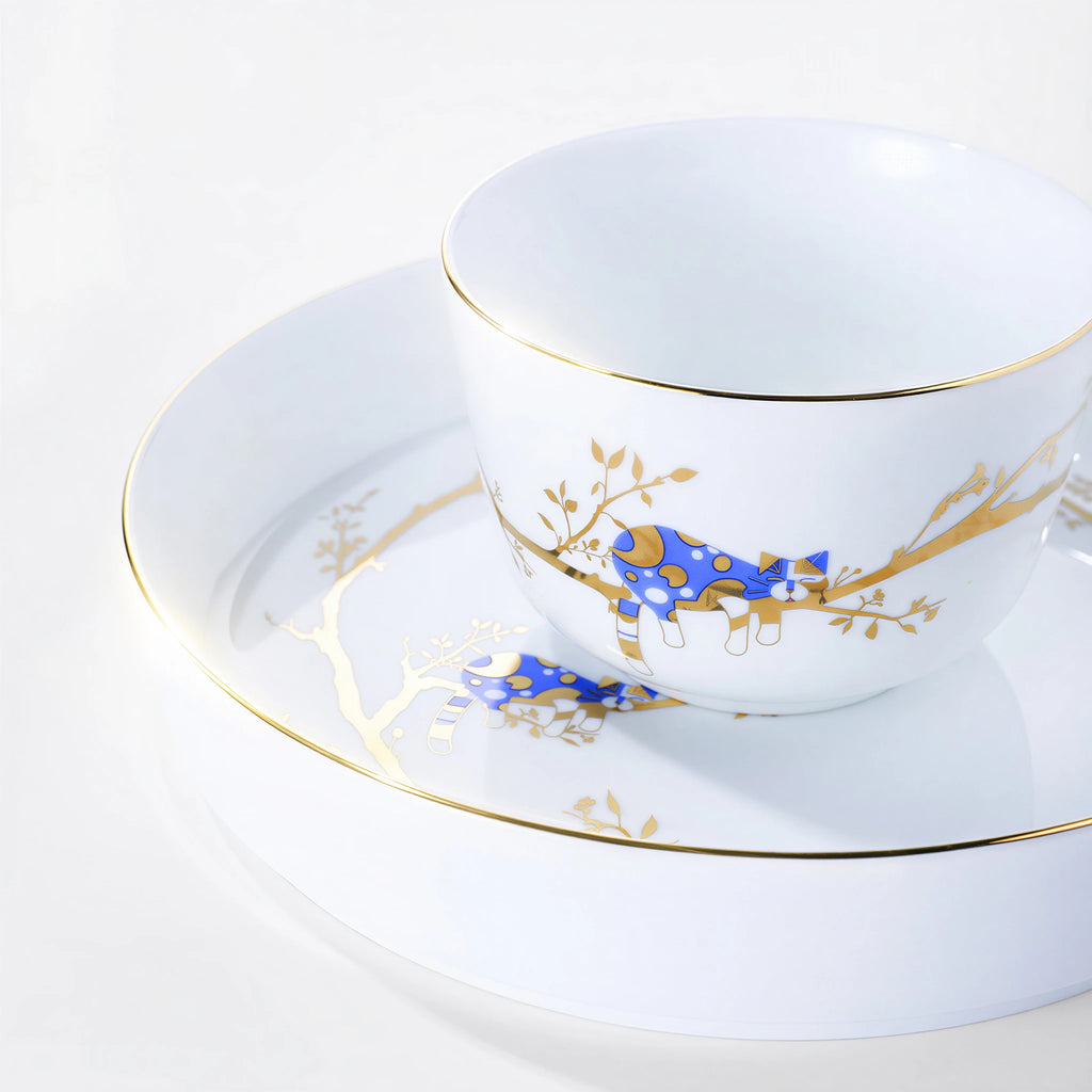 Forest Rest rice bowl with a cobalt-blue cat, gold branches, and a fine gold-colored rim above stacked plates.