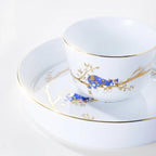 Forest Rest rice bowl with a cobalt-blue cat, gold branches, and a fine gold-colored rim above stacked plates.