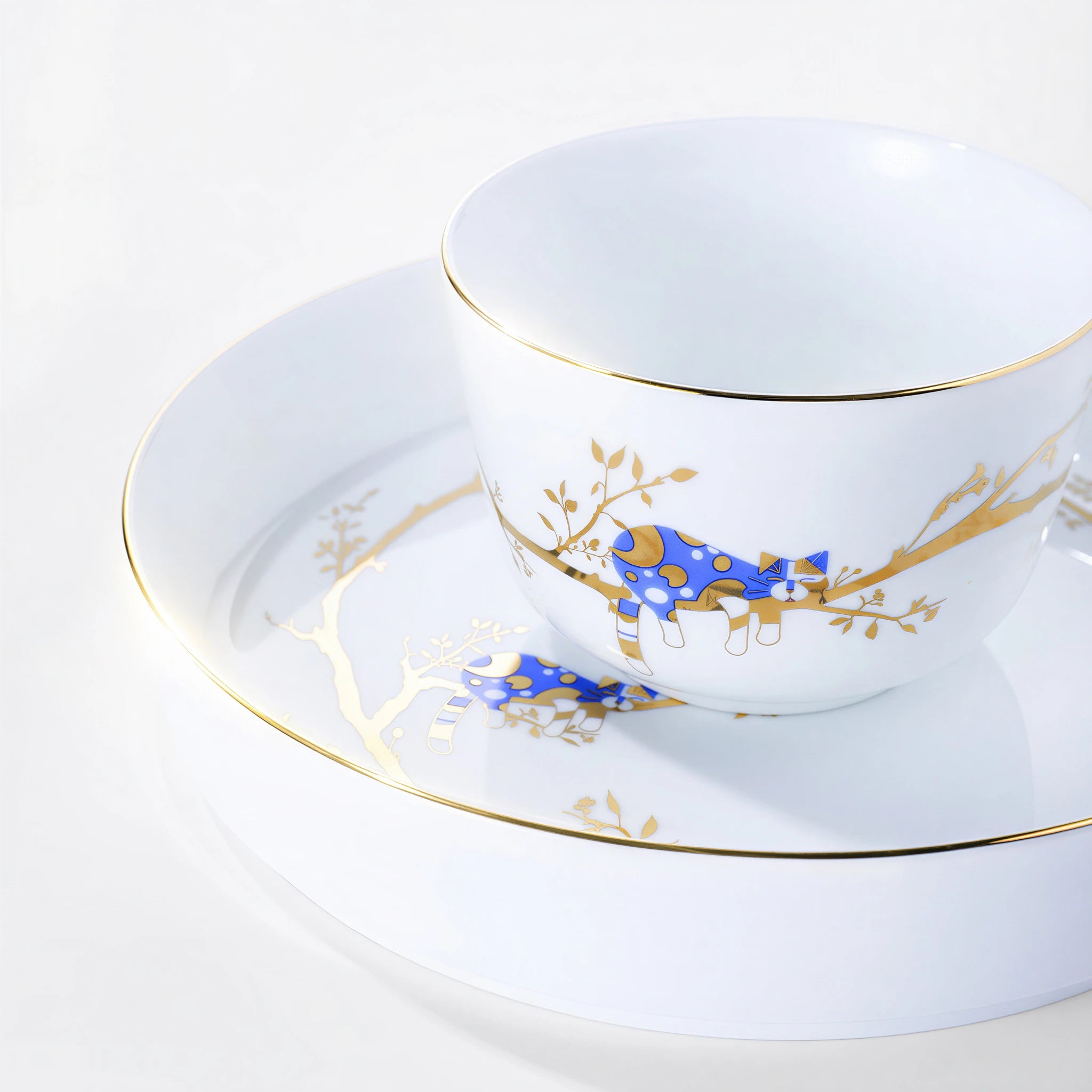 Forest Rest rice bowl with a cobalt-blue cat, gold branches, and a fine gold-colored rim above stacked plates.