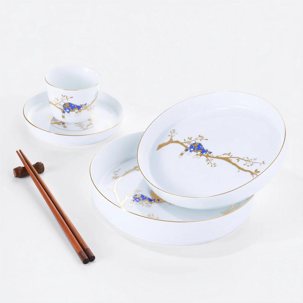 White porcelain Forest Rest place setting with three plates, a rice bowl, a cup, and wooden chopsticks.