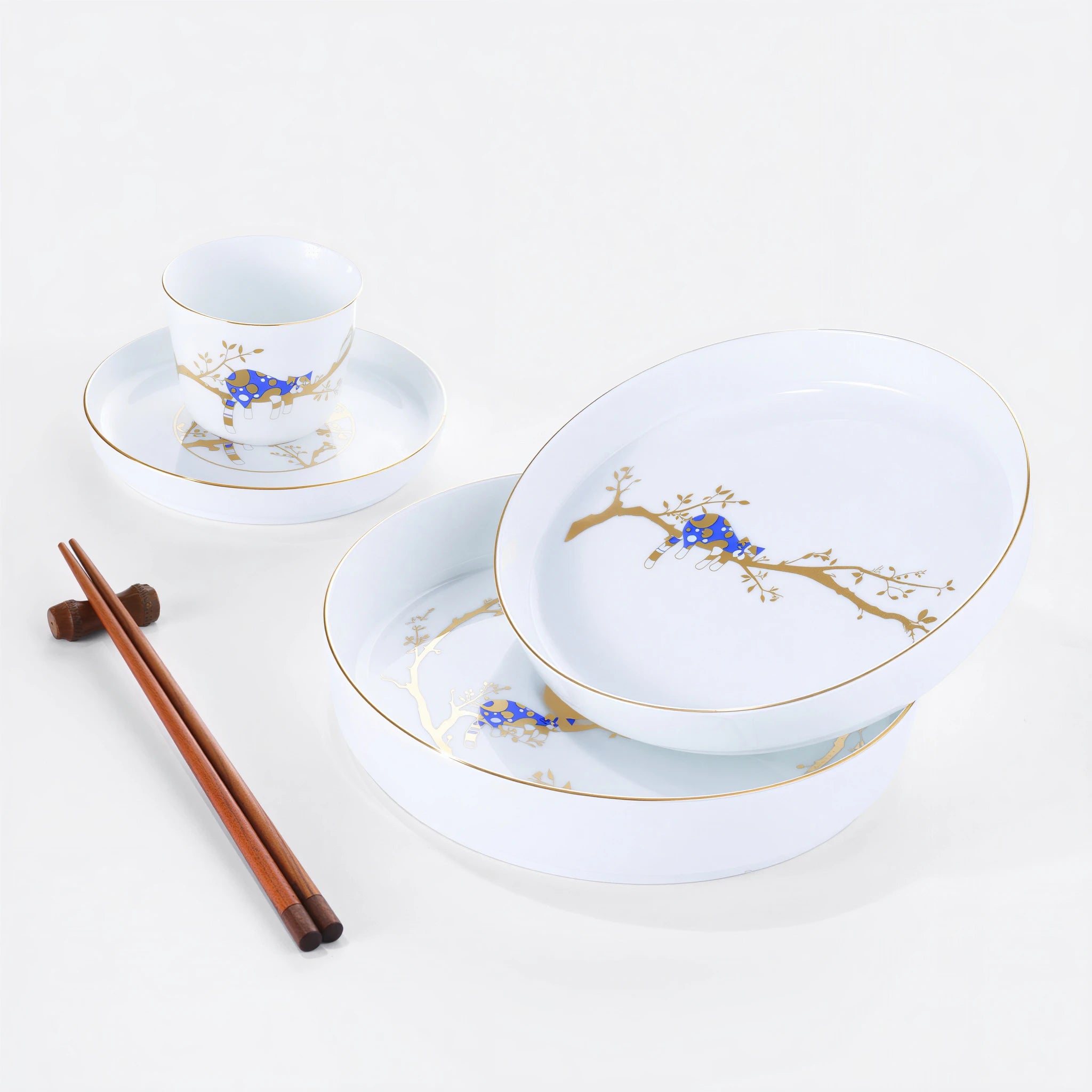 White porcelain Forest Rest place setting with three plates, a rice bowl, a cup, and wooden chopsticks.