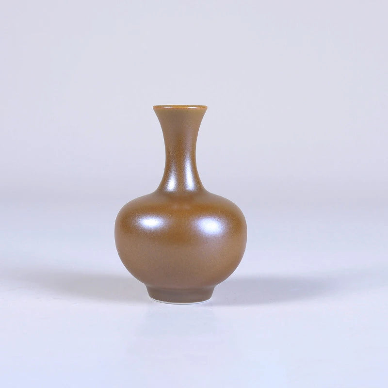 Globular maple-yellow mini porcelain vase with a narrow mouth.
