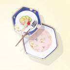 Two faceted Courtyard in Bloom porcelain plates styled with food, showing navy and blush floral fields.