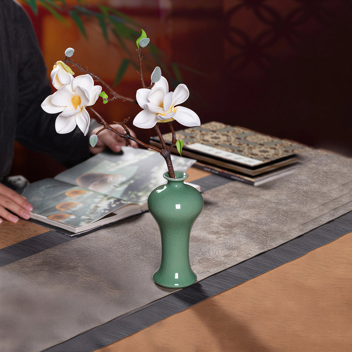 Hand arranging a magnolia stem in the Longquan bud vase