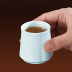 Hand holding a begonia-ribbed Yingqing cup with tea