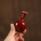 Mini oxblood red porcelain vase held in one hand