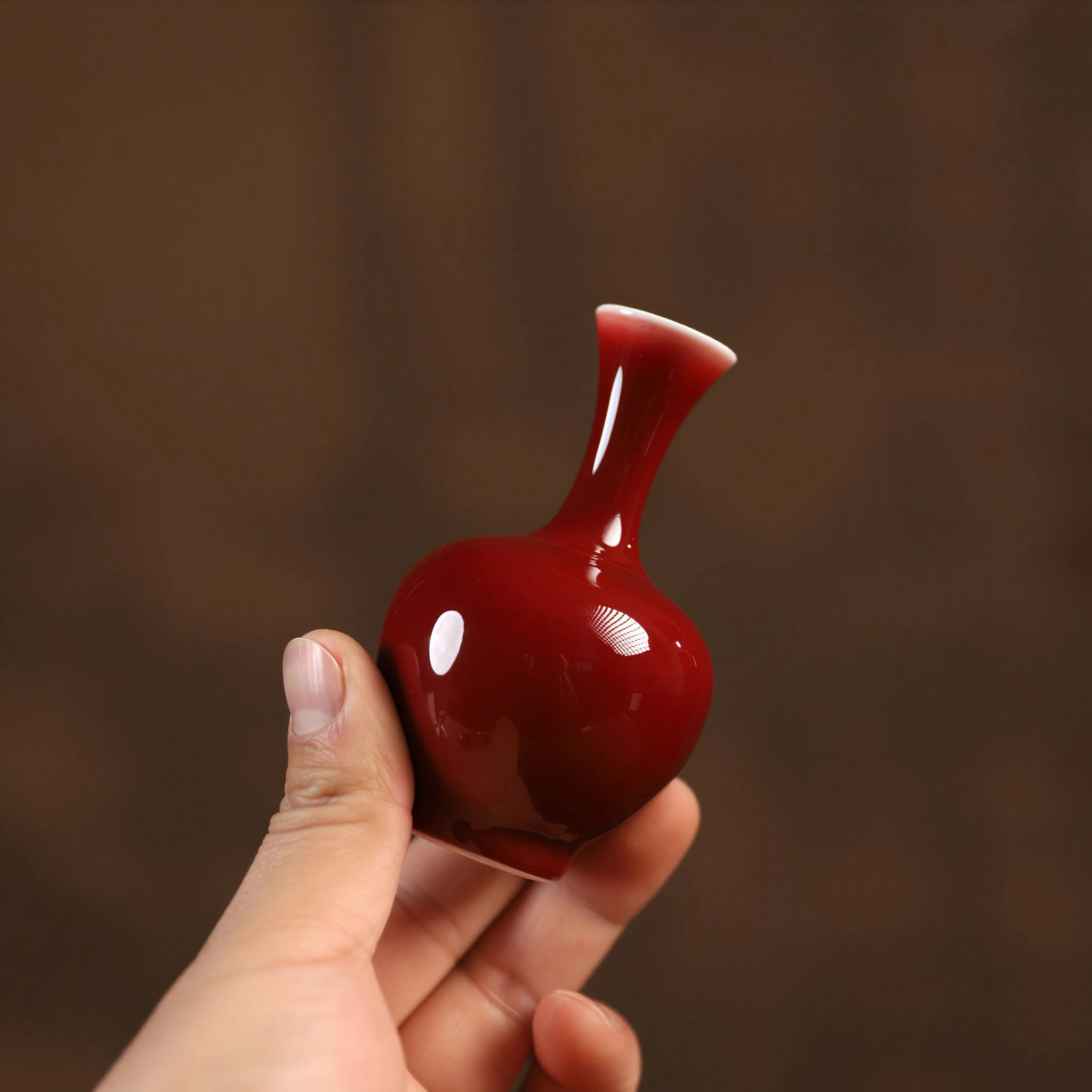 Mini oxblood red porcelain vase held in one hand