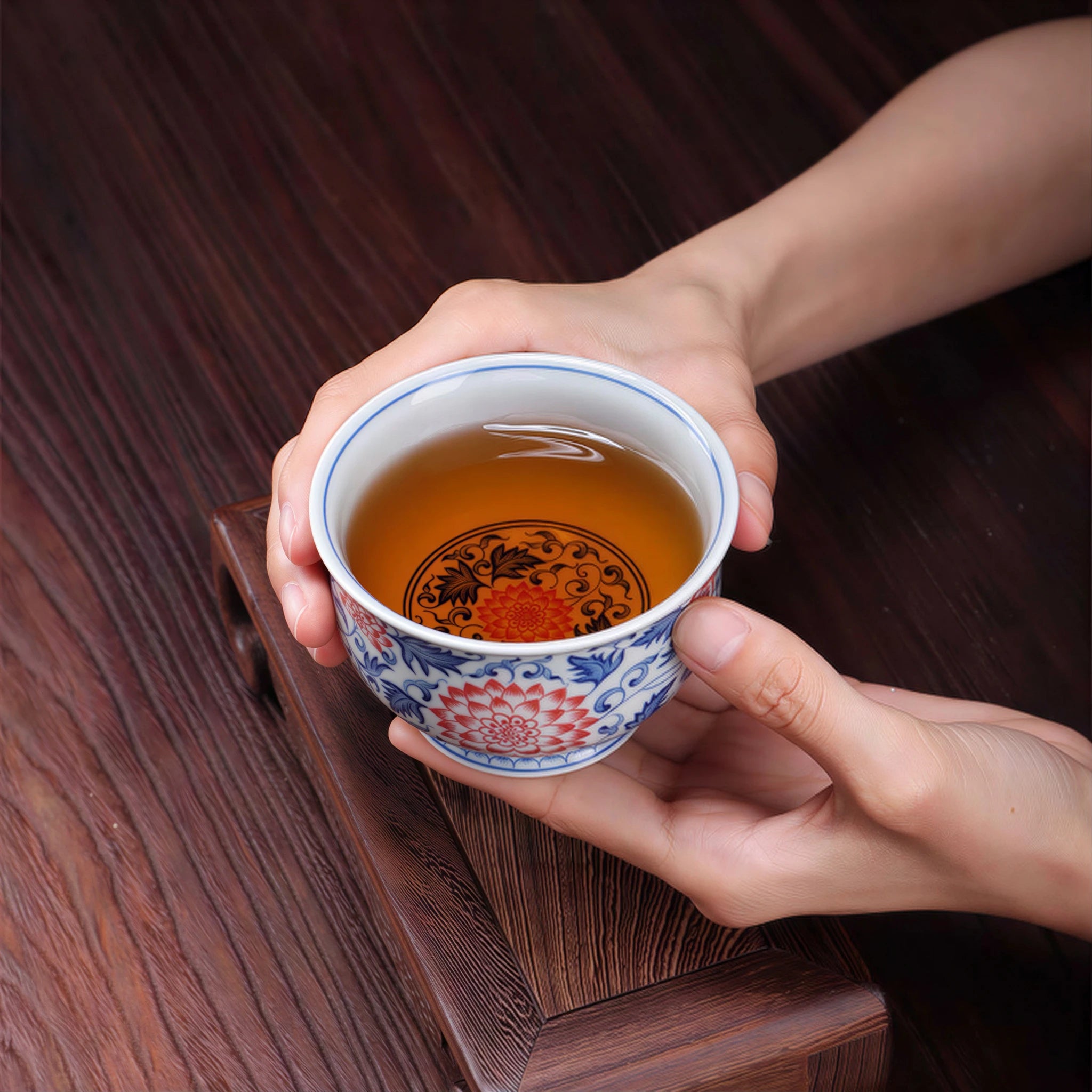 Red and blue lotus teacup held with tea