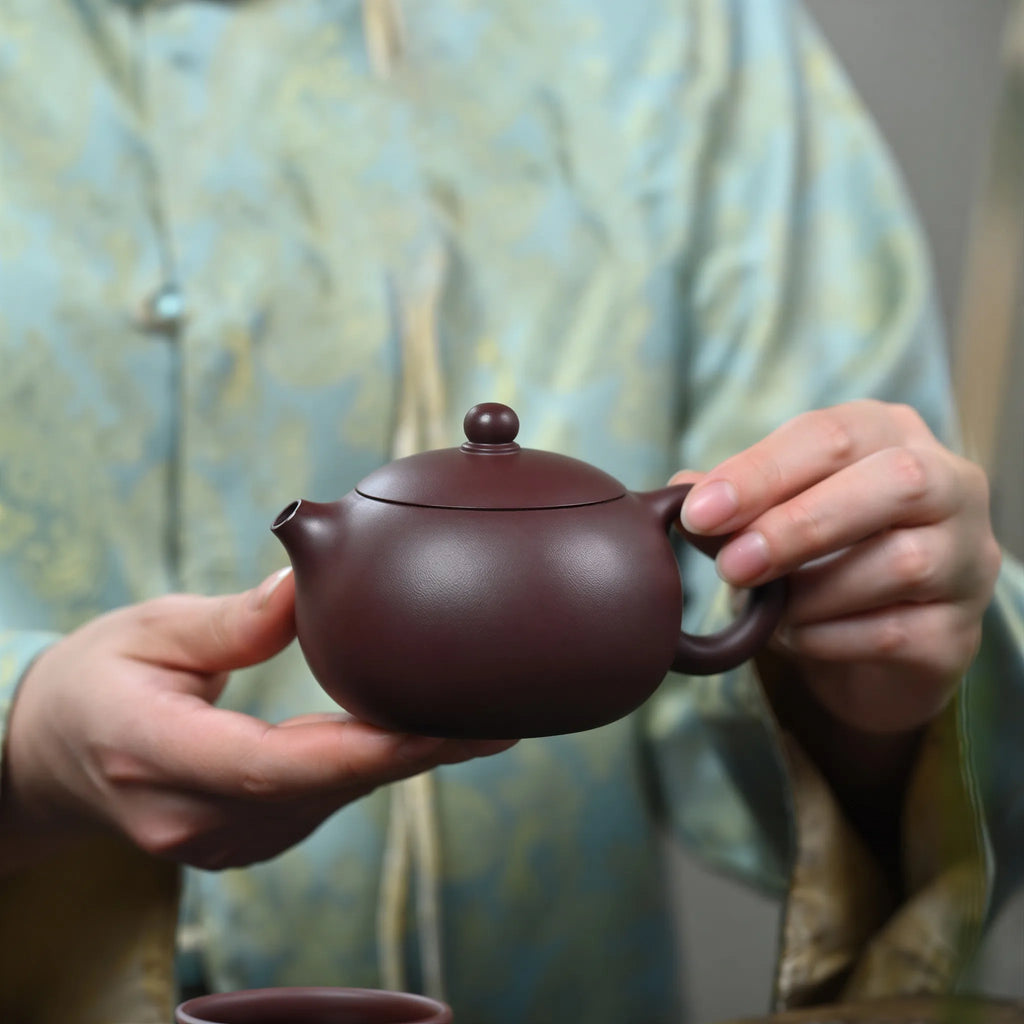 Rounded zini Xishi teapot held in one hand