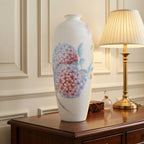 White porcelain hydrangea Meiping vase displayed beside a brass table lamp on a wood sideboard