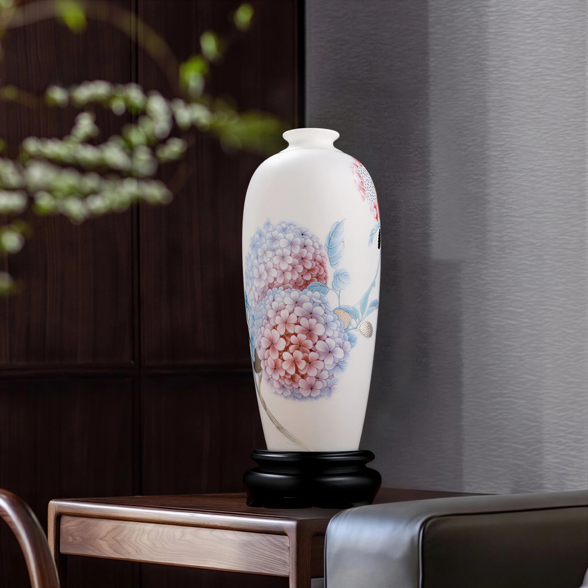 Hydrangea Meiping vase on its dark wooden stand on a cabinet beside an upholstered chair