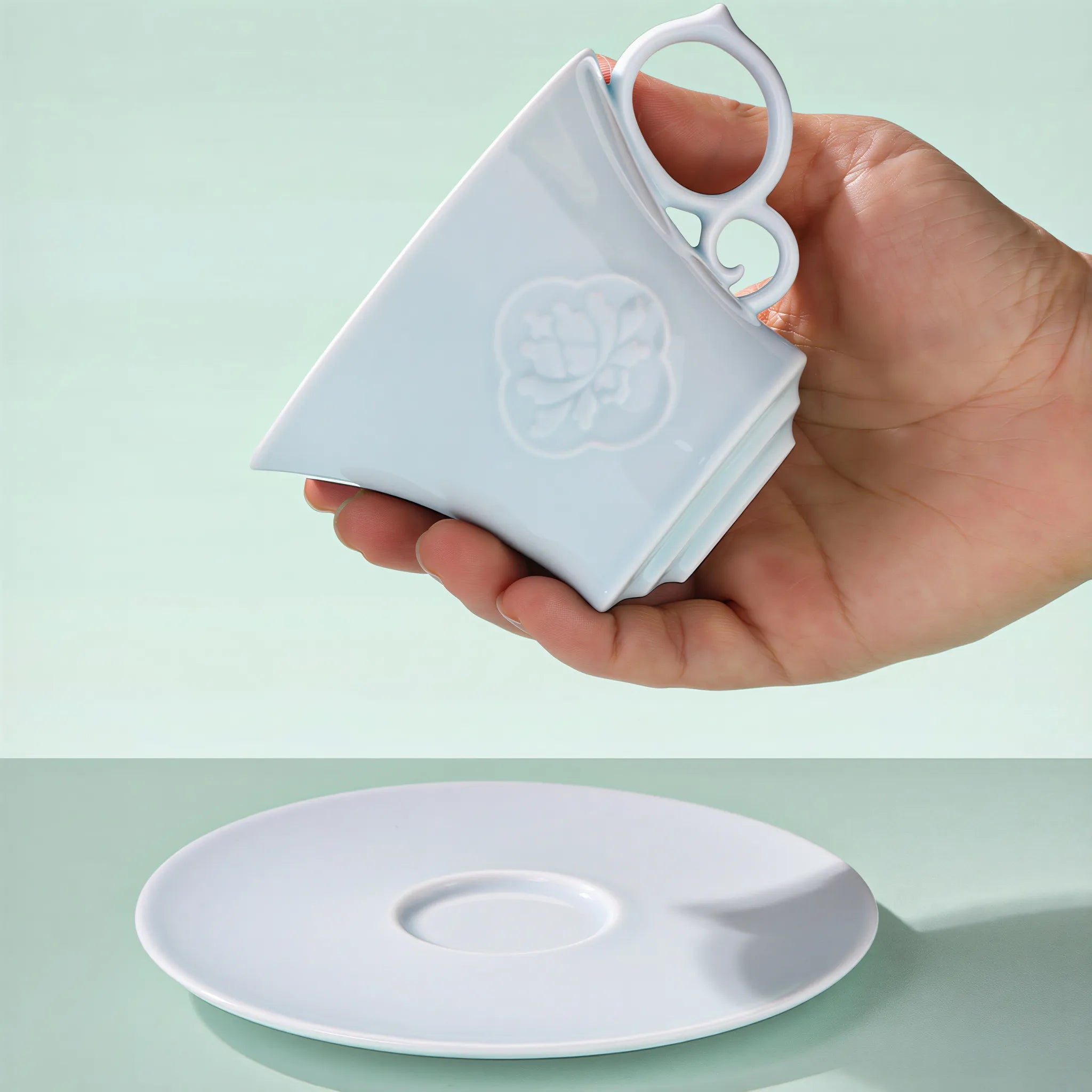 Carved peony porcelain coffee cup held in hand