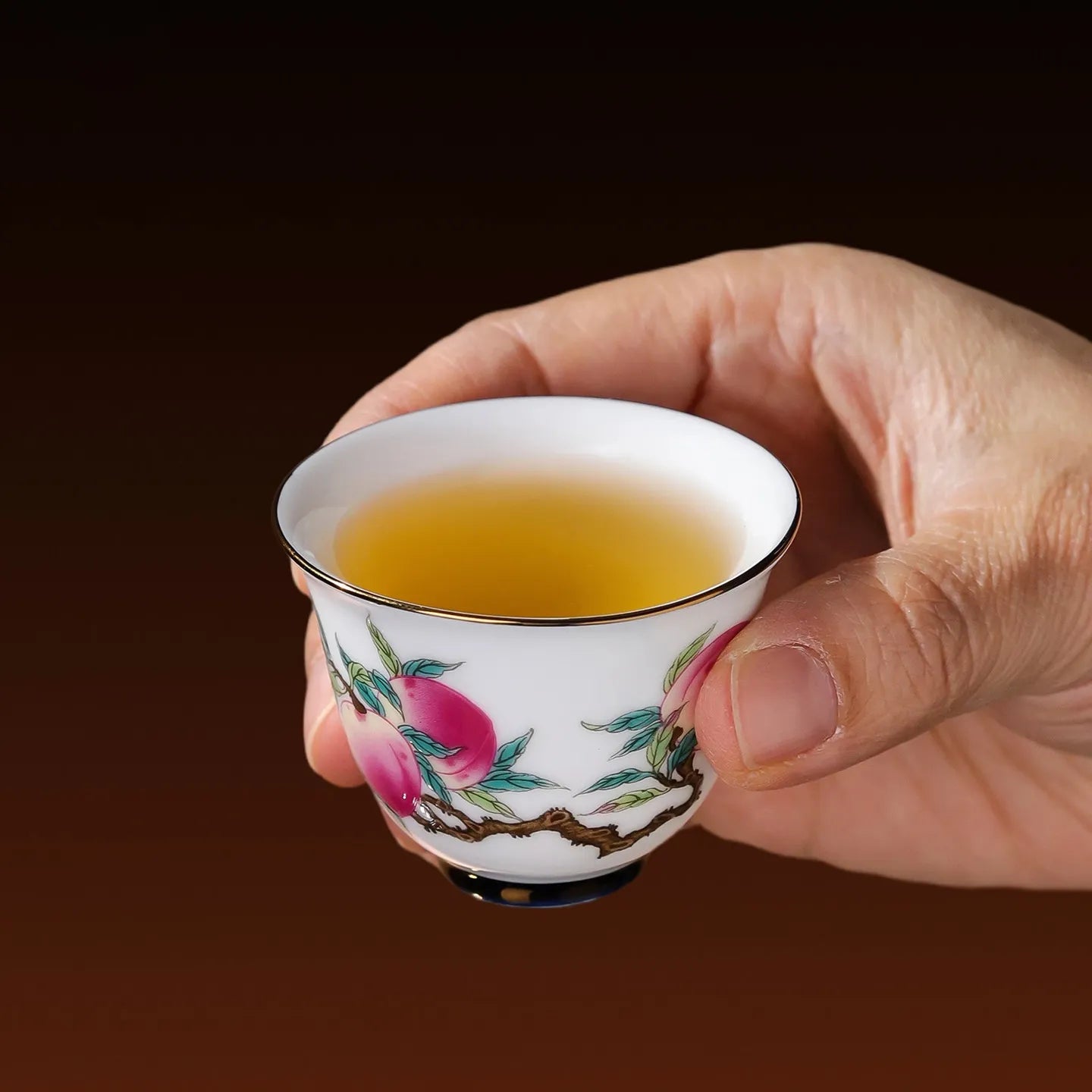 Famille rose peach tasting cup held in hand