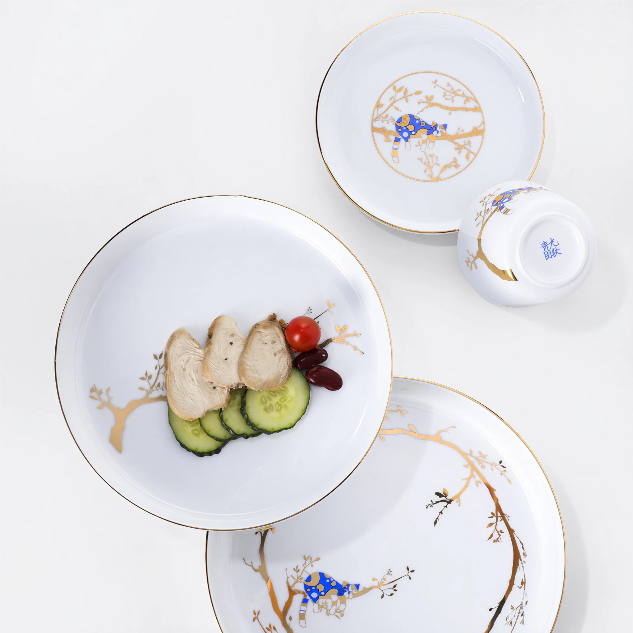Overhead view of the five-piece Forest Rest tableware set with food on one plate and a blue base mark visible on the inverted bowl.