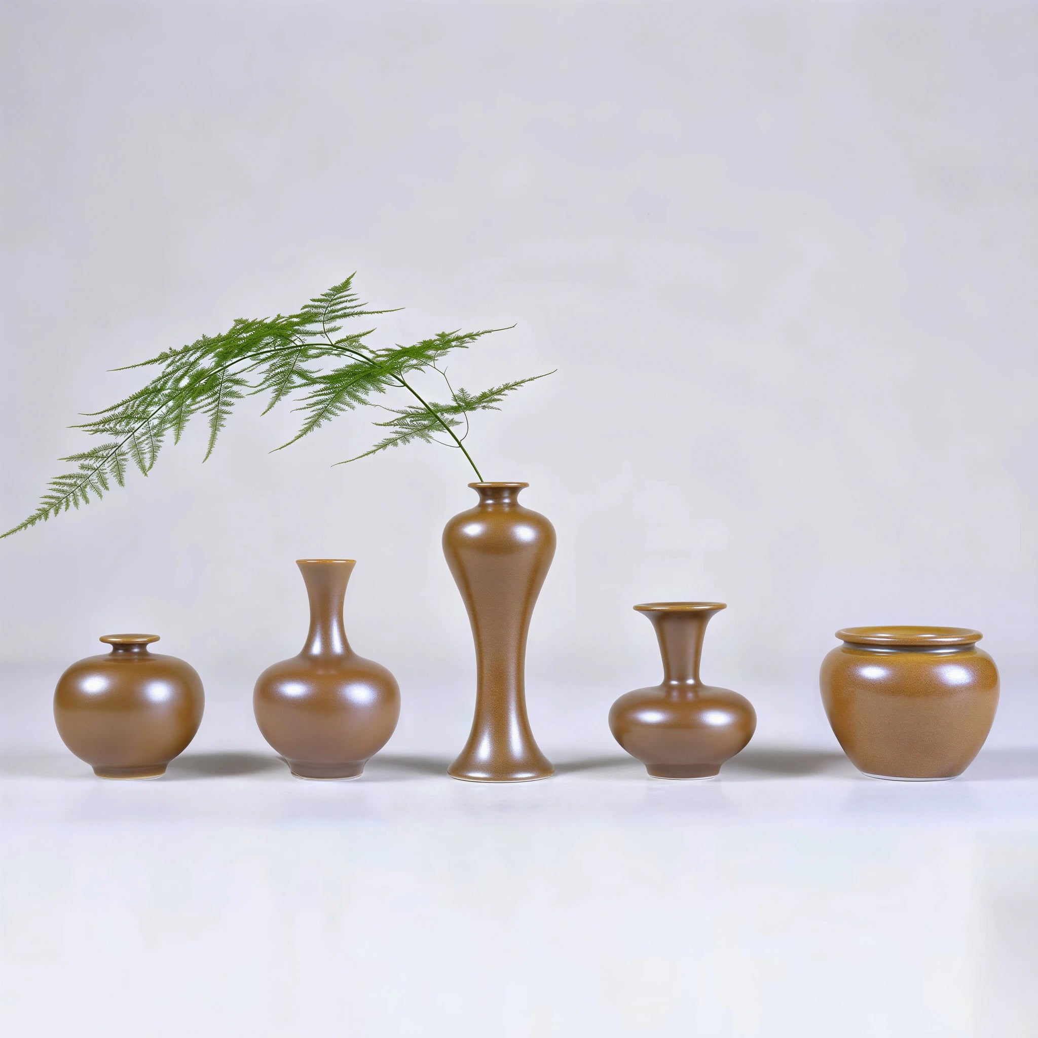 Five hand-thrown Jingdezhen maple-yellow mini porcelain vases arranged with a fern stem.
