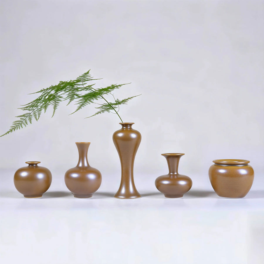 Five maple-yellow Jingdezhen miniature porcelain vases arranged with a fern stem