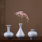 Three pale-blue crackle-glaze Jingdezhen vases with a small pink flower spray.