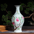 Famille rose peach and bat olive vase beside a bonsai