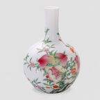 Front view of a white porcelain Tianqiu vase with pink peaches, open pomegranates and green leaves.