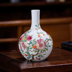 Peach and pomegranate porcelain vase displayed on a dark wooden table.