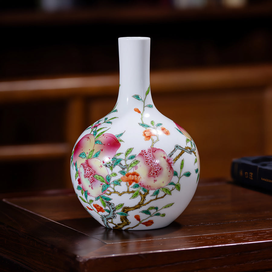 Peach and pomegranate porcelain vase displayed on a dark wooden table.