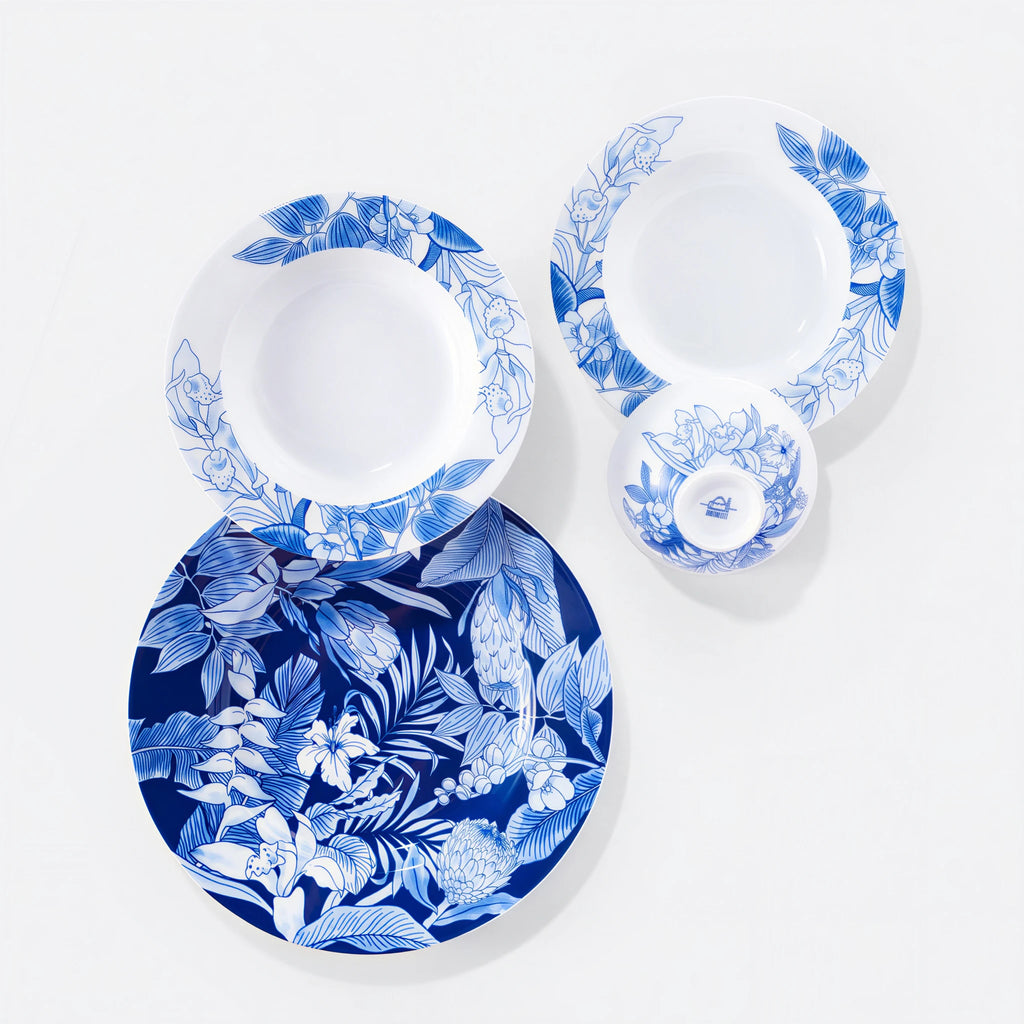 Overhead view of a large botanical plate, two deep plates, and a porcelain rice bowl.