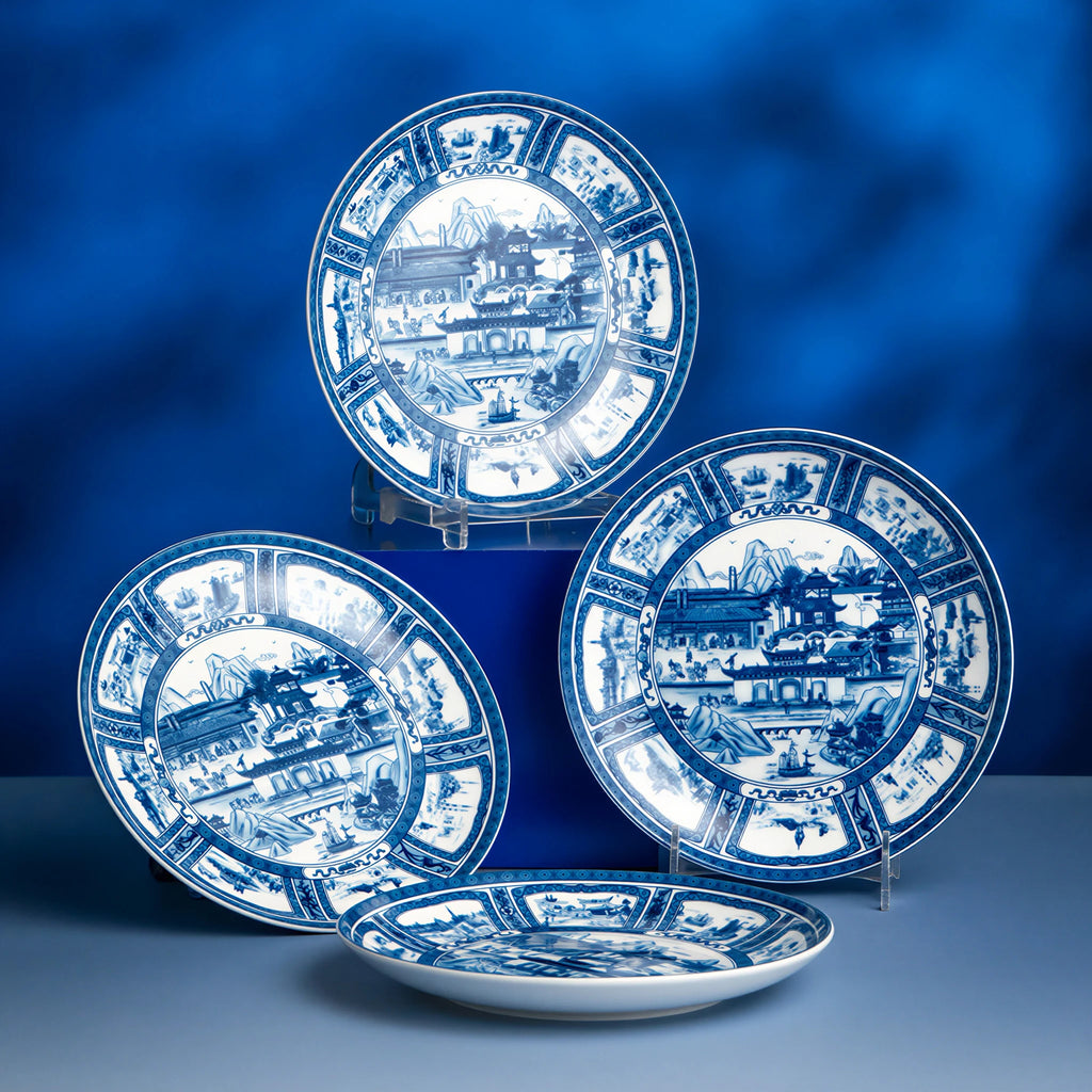 Three Silk Road porcelain plates displayed upright and flat against a blue backdrop.