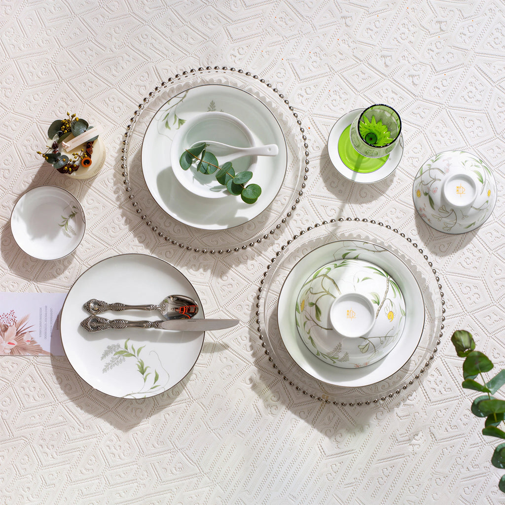 Overhead view of Spring Dawn porcelain bowls, plates, dishes, and spoons with one bowl turned to show its orange underside mark.