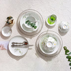 Overhead view of Spring Dawn porcelain bowls, plates, dishes, and spoons with one bowl turned to show its orange underside mark.
